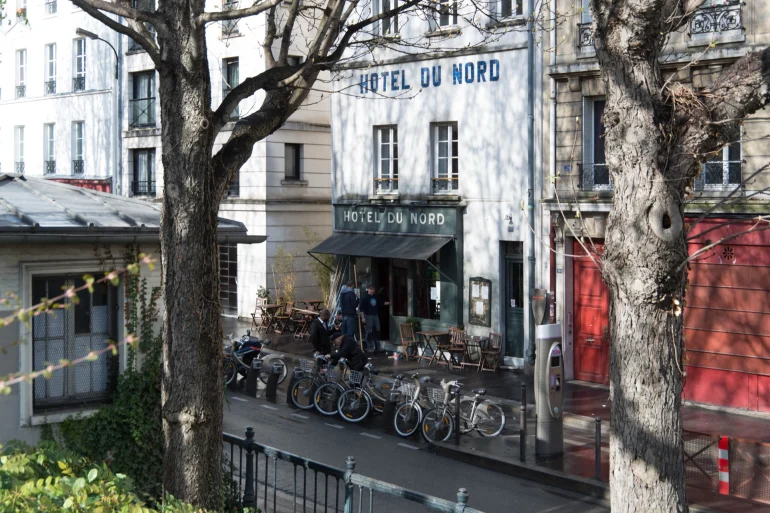 Façade de l'Hôtel du Nord, 102 quai de Jemmapes à Paris, terrasse au store rouge et vélos sur le canal Saint-Martin