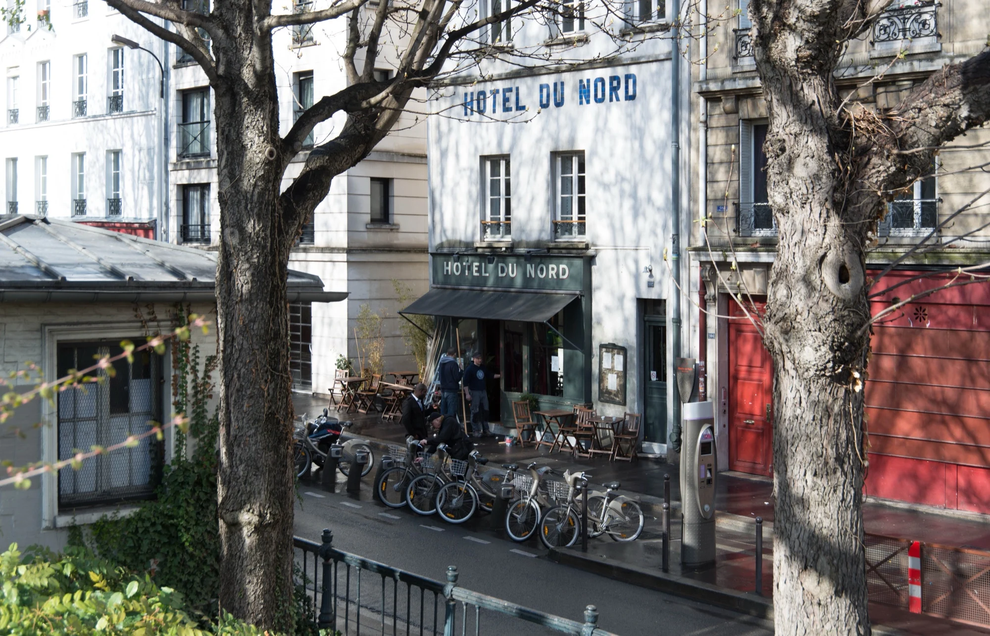 Façade de l'Hôtel du Nord, 102 quai de Jemmapes à Paris, terrasse au store rouge et vélos sur le canal Saint-Martin