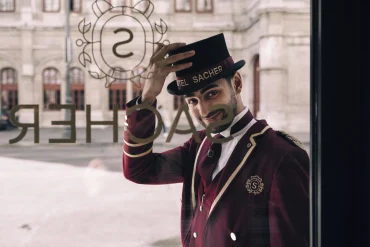 Un portier en livrée devant la vitrine de l’Hotel Sacher Wien