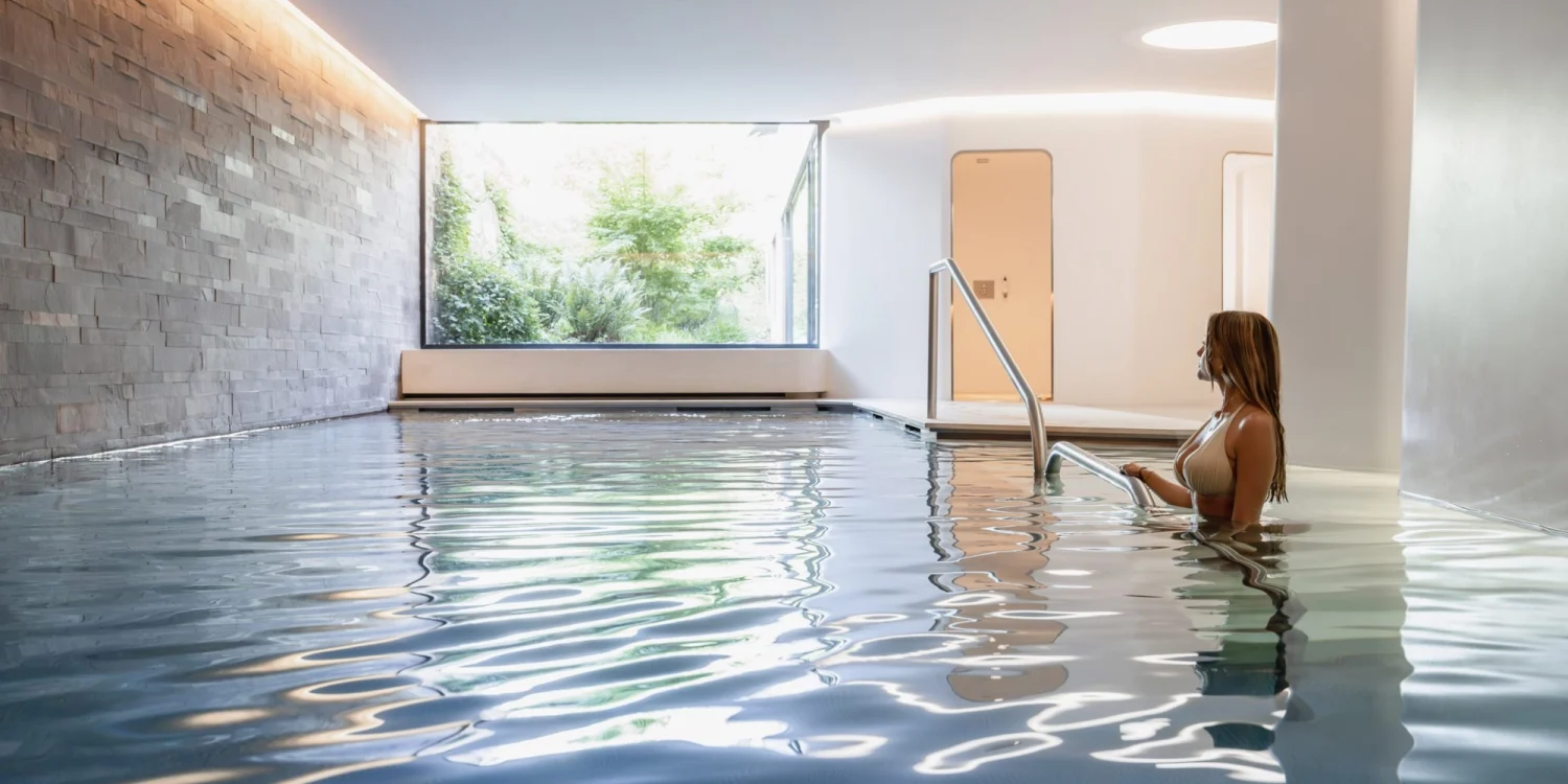 La piscine intérieure de 17 mètres du spa des Haras Hôtel, à Strasbourg, éclairée par une baie vitrée ouverte sur la végétation