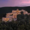 The Oberoi Rajgarh Palace, palais Bundela éclairé au crépuscule sur une colline boisée près de Khajuraho