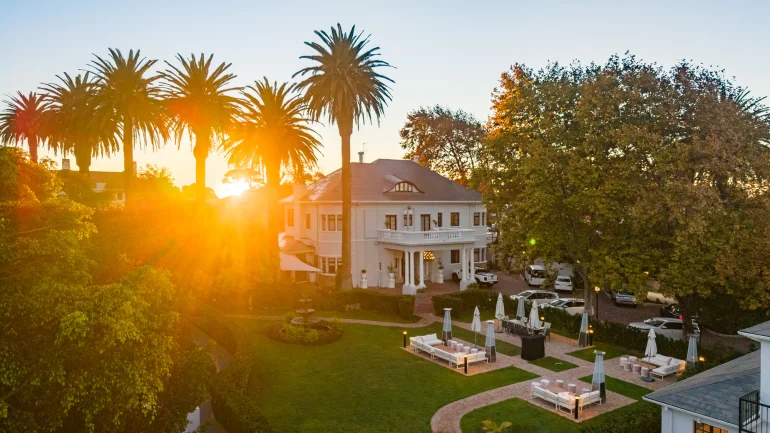 Le manoir du Palm House Boutique Hotel & Spa au Cap au coucher du soleil, pelouse et terrasses de jardin sous les palmiers de Wynberg