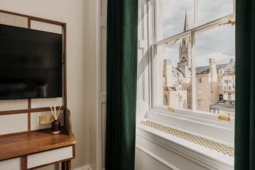 Chambre du Parade Hotel Bath avec tête de lit rouge, cheminée d'époque et fenêtre à guillotine géorgienne