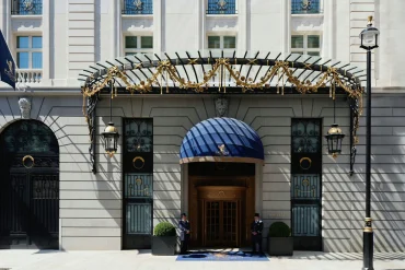 Entrée principale de l'hôtel : marquise en fer forgé doré, auvent bleu, deux portiers en livrée