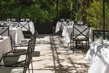 Tables nappées de blanc de Maison Roland, le bistrot du jardin du Shangri-La Paris, sous les arbres de l'avenue d'Iéna