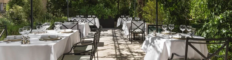 Tables nappées de blanc de Maison Roland, le bistrot du jardin du Shangri-La Paris, sous les arbres de l'avenue d'Iéna