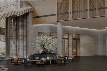 Lobby à double hauteur du Shilla Monogram Hanoi West Lake, claustras de bois ajouré, colonnes de pierre et salon devant les baies vitrées