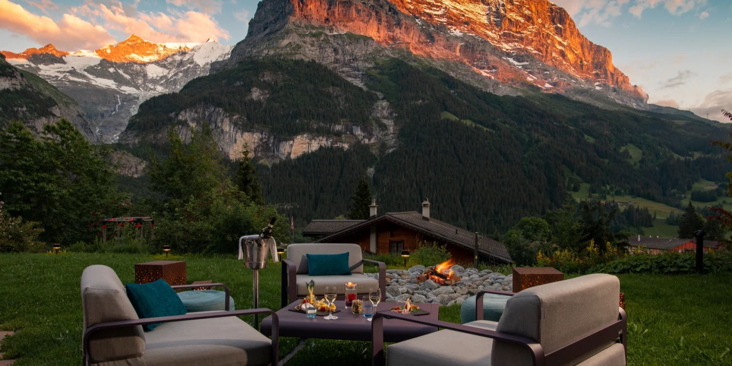 Le salon de jardin du Sunstar Hotel Grindelwald, feu de camp et fauteuils face à la face nord de l'Eiger rougeoyante au coucher du soleil