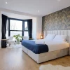 Chambre rénovée du Tall Trees Hotel à Amlwch, sur l'île d'Anglesey au pays de Galles, tête de lit capitonnée et papier peint bleu