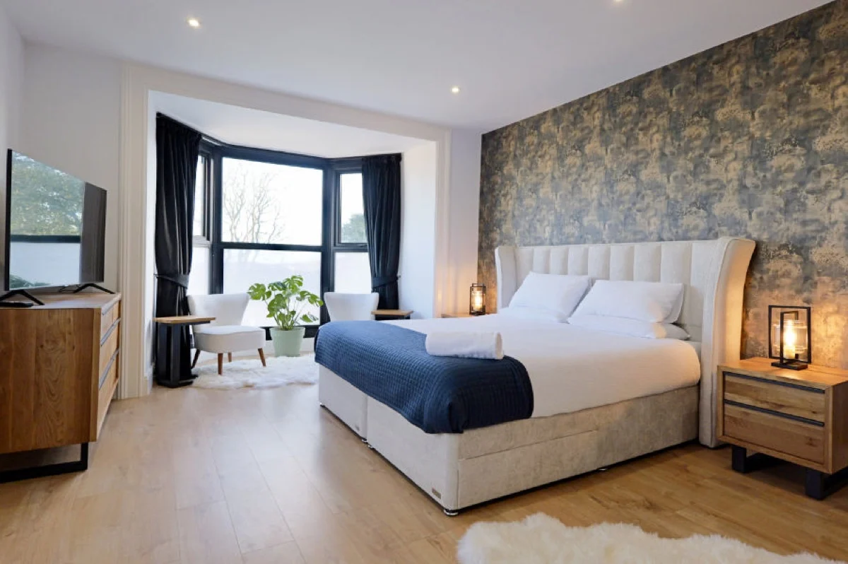 Chambre rénovée du Tall Trees Hotel à Amlwch, sur l'île d'Anglesey au pays de Galles, tête de lit capitonnée et papier peint bleu