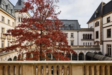 La cour intérieure de l'hôtel The Florentin à Francfort, arbre rouge d'automne devant la villa de 1901 et ses arcades