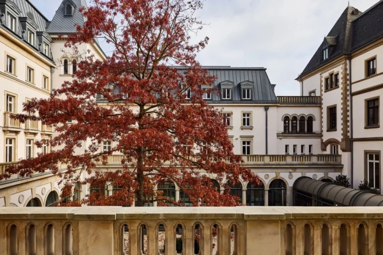La cour intérieure de l'hôtel The Florentin à Francfort, arbre rouge d'automne devant la villa de 1901 et ses arcades