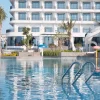Facade blanche du Tra Co Long Beach Hotel & Resort a Mong Cai vue depuis la grande piscine exterieure bordee de palmiers