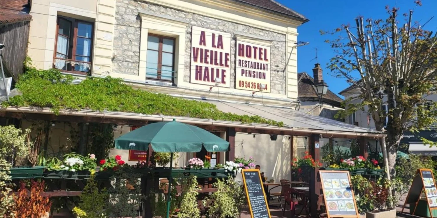Façade de l'hôtel À la Vieille Halle à Souppes-sur-Loing, avec son enseigne et sa terrasse fleurie