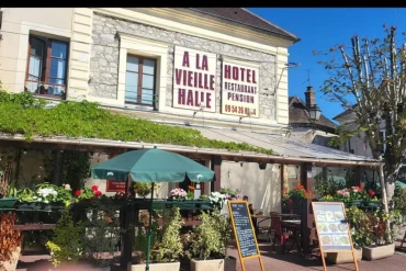Façade de l'hôtel À la Vieille Halle à Souppes-sur-Loing, avec son enseigne et sa terrasse fleurie