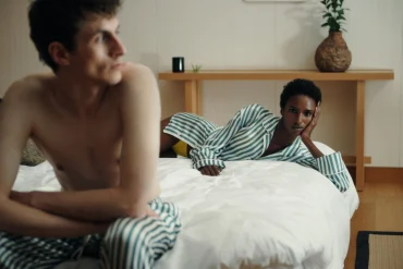 Pyjamas en soie rayés Aman x Kim Jones portés dans une chambre au décor épuré