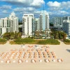 La plage de l'Andaz Miami Beach, ses parasols orange et les immeubles de Mid-Beach