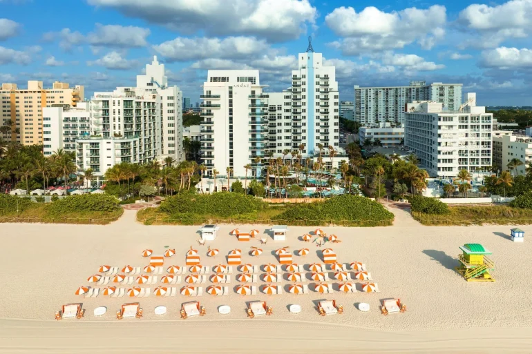 La plage de l'Andaz Miami Beach, ses parasols orange et les immeubles de Mid-Beach