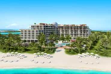 Rendu de l'Andaz Turks & Caicos at Grace Bay vu depuis la plage de Grace Bay, ses deux bâtiments, ses palmiers et ses transats