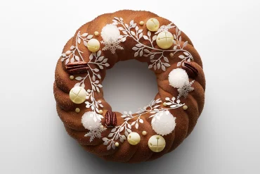 La Bûche de Noël Couronne 2026 du Mandarin Oriental Lutetia, Paris, couronne torsadée ornée de grelots en chocolat blanc et de feuilles d'azyme