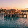 Rendu des bungalows sur pilotis du Four Seasons Resort Caye Chapel, au Belize, au coucher du soleil