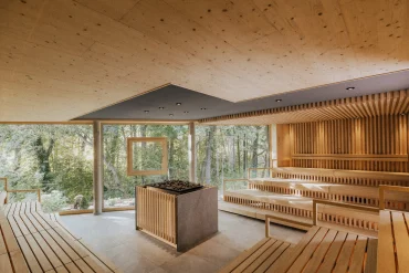 Les gradins en bois clair du Quell-Sauna, ouverts sur la forêt, au Heilthermen Resort de Bad Waltersdorf