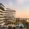Rendu de l'Ampersand Beach House, Colbert Collection, sur Dubai Islands : façade en terrasses, piscine et plage au coucher du soleil