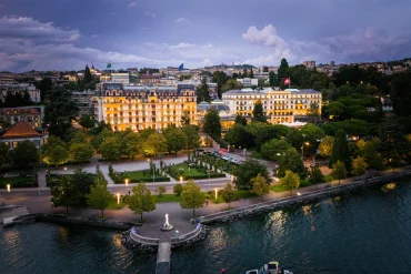 Vue aérienne du Beau-Rivage Palace à Lausanne au crépuscule, entre ses jardins et le lac Léman