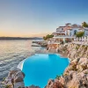 La piscine creusée dans la roche et le pavillon Eden-Roc de l'Hôtel du Cap-Eden-Roc au coucher du soleil, au Cap d'Antibes