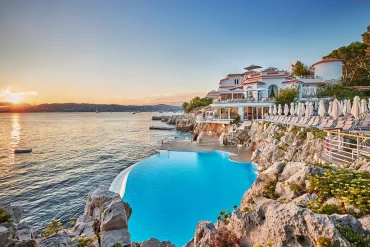 La piscine creusée dans la roche et le pavillon Eden-Roc de l'Hôtel du Cap-Eden-Roc au coucher du soleil, au Cap d'Antibes
