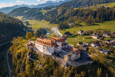 Vue aérienne de l'hôtel Castel Badia sur son éperon au-dessus du val Pusteria, dans les Dolomites