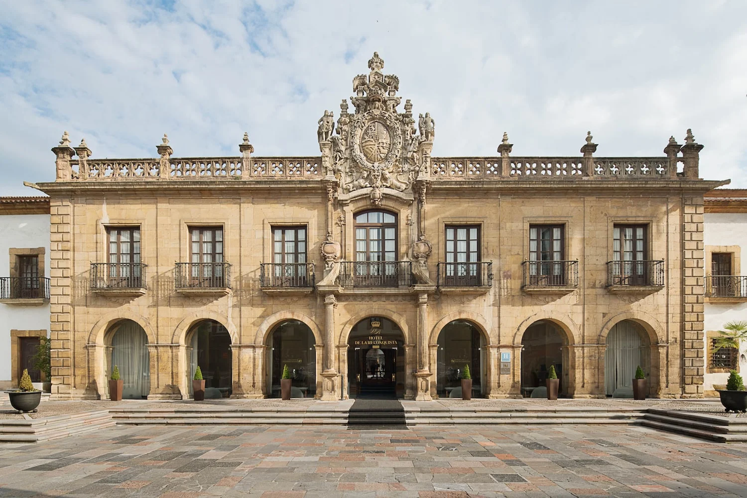Façade baroque en pierre de l'hôtel Eurostars de la Reconquista à Oviedo, avec ses arcades et le grand blason sculpté