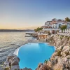 La piscine d'eau de mer taillée dans le roc de l'Hôtel du Cap-Eden-Roc au coucher du soleil, face à la baie de Juan-les-Pins
