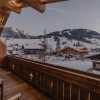 Vue depuis un balcon en bois de l’hôtel Fouquet’s Gstaad sur les chalets enneigés et les sommets