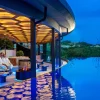 Sky-Lounge du Wellness- & Sporthotel Jagdhof à Röhrnbach, feu décoratif au bord du Sky Infinity-Pool en granit à la tombée de la nuit