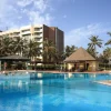La piscine du King Fahd Palace à Dakar, entourée de cocotiers, devant la façade de l'hôtel