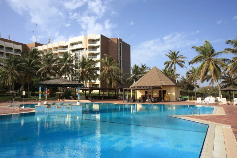La piscine du King Fahd Palace à Dakar, entourée de cocotiers, devant la façade de l'hôtel