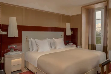 Chambre d'une Executive Suite du Graal Cortina, laque rouge, lit king size et fenêtre ouverte sur les Dolomites