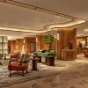 Lobby du premier étage de l'hôtel Mandarin Oriental The Landmark à Hong Kong, redessiné par Joyce Wang dans des tons terre cuite et vert profond