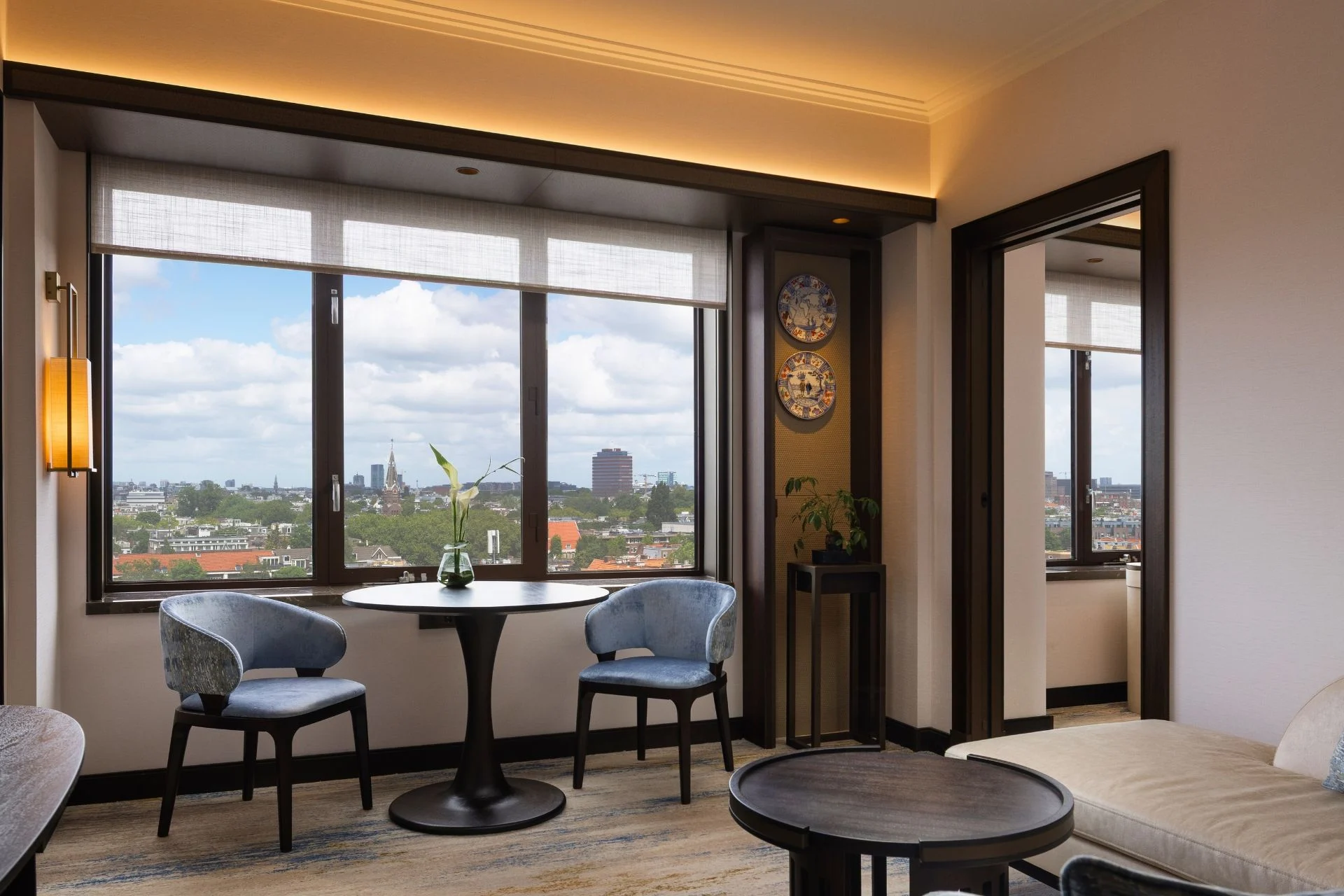 Salon d'une Panorama Signature Suite de l'hôtel Okura Amsterdam, table ronde face aux fenêtres sur la ville