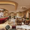 Rendu du bar lounge de l'hôtel Six Senses Milan, comptoir rouge et colonnes de marbre veiné