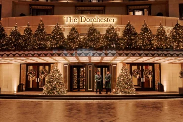 La façade de l'hôtel The Dorchester sur Park Lane à Londres, illuminée de sapins de Noël, avec deux portiers en livrée