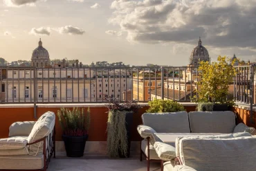 Terrasse du LYVE Rooftop du Thompson Rome avec canapés et vue sur les coupoles et les toits de Rome au coucher du soleil