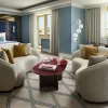 Chambre et coin salon de la suite présidentielle rénovée du Tivoli Avenida Liberdade à Lisbonne, murs bleus et fauteuils arrondis