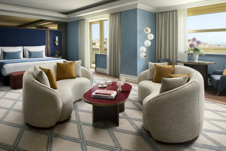 Chambre et coin salon de la suite présidentielle rénovée du Tivoli Avenida Liberdade à Lisbonne, murs bleus et fauteuils arrondis