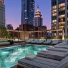 Rendu de la piscine extérieure sur le toit du Viceroy Park Avenue à New York, transats rayés face à l'Empire State Building au crépuscule