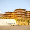Rendu de l'hôtel Lily of the Valley Courchevel, façades en bois et terrasses au bord de la piste de l'altiport, un avion stationné devant
