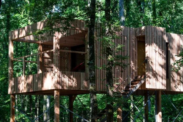 Un lodge perché sur pilotis de Loire Valley Lodges, bardage de bois et grandes baies vitrées, au milieu des arbres de la forêt de la Duporterie en Touraine