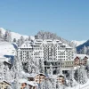 Le Carlton Hotel St. Moritz au-dessus du village enneigé et des sapins, en Engadine, Suisse