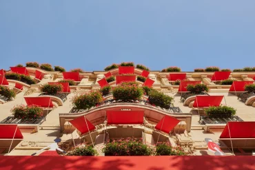 La façade de l'Hôtel Plaza Athénée avenue Montaigne à Paris, avec ses stores rouges et ses géraniums, hôtel de Miranda Priestly dans Le Diable s'habille en Prada